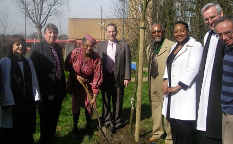 Local politicians and activists gather to watch Mrs Zena Edmund-Charles plant her tree
